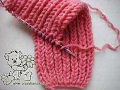 a pink knitted mitt sitting on top of a white table next to a pair of scissors