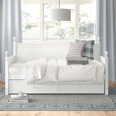 a white day bed with pillows and blankets on it