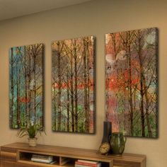 three paintings hanging on the wall above a book shelf