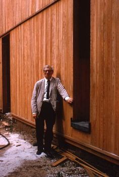 a man leaning against the side of a wooden building