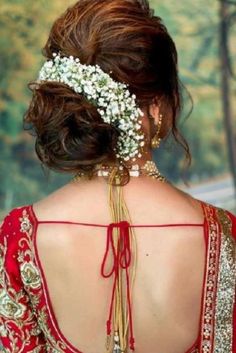 the back of a woman's head wearing a red dress with white flowers in her hair