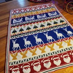 a multicolored knitted christmas rug with reindeers and santa's sleigh