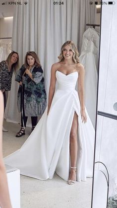 a woman in a white dress standing next to a mirror