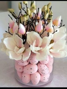 a vase filled with pink and white flowers on top of a table next to eggs