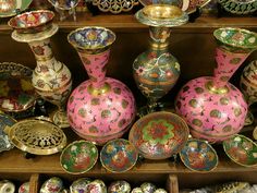 many colorful vases and bowls are on display in a store shelf with other items