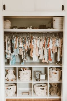 a closet filled with lots of baby clothes and stuffed animals on top of white shelves