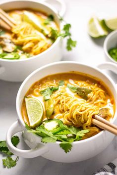 three bowls of soup with chopsticks on the side and lime slices around them