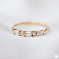 a gold ring with three baguets on it, sitting on a white cloth