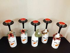 four white vases with red and black lids decorated with christmas decorations, one has a penguin face on it