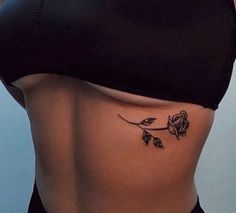 a woman's stomach with a rose tattoo on her lower side, which is black