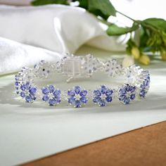 This exquisite floral bracelet is the epitome of elegance and beauty. Crafted from sterling silver, it features genuine gemstones in a stunning floral design that is sure to turn heads. The intricate detailing of each gemstone adds a touch of sophistication and luxury to any outfit. Whether you're dressing up for a special occasion or simply want to add a touch of glamour to your everyday look, this bracelet is the perfect choice. Item Details- Metal- Sterling Silver Stone- Tanzanite Shape- Pear 4x3mm Total Weight- 19.50 Ct. Approx Setting- Prong Finish- Platinum Overlay Clasp- Box Elegant Silver Bracelets With Flower Shape, Elegant Silver Bracelets In Flower Shape, Elegant Silver Flower-shaped Bracelets, Elegant Sterling Silver Flower Bracelet, Delicate Silver Gemstone Bracelets, Elegant Sterling Silver Flower Bracelets, Silver Tanzanite Bracelet Fine Jewelry, Silver Tanzanite Bracelet In Fine Jewelry Style, Delicate Silver Bracelets With Ethical Gemstones