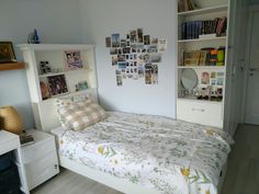 a bed sitting in a bedroom next to a white book shelf filled with books on top of it