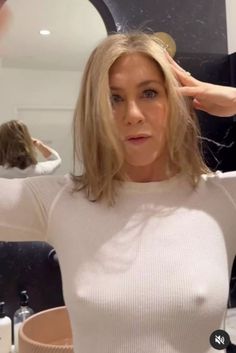 a woman is getting her hair done in front of a mirror and looking at the camera