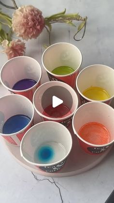 a bunch of cups that are sitting on a table with some paint in the middle