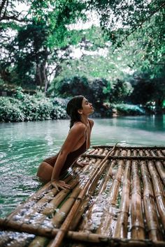 a woman sitting on top of a bamboo raft in the water