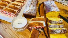 several different types of bread on a wooden cutting board with butter and powdered sugar