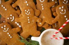 several gingerbread cookies with white icing and sprinkles next to a cup of coffee