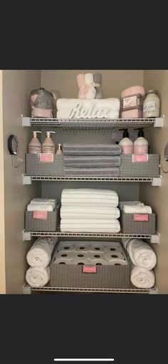 the shelves are organized with towels, blankets and other household care products in grey baskets