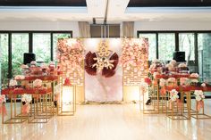 a room filled with lots of tables covered in flowers and gold stands next to large windows