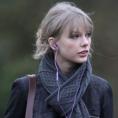 a close up of a person with ear buds in their ears and wearing a scarf