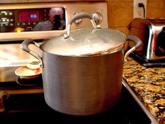 a large pot sitting on top of a stove next to an oven with a microwave in the background