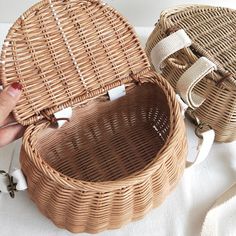 two wicker baskets sitting next to each other on a white cloth covered tablecloth