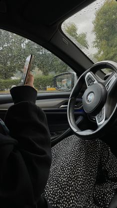 a person sitting in the driver's seat of a car holding a cell phone