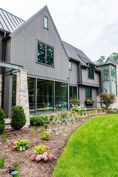 a large house with lots of windows and flowers in the front garden area next to it