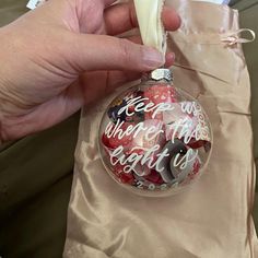 a hand holding a christmas ornament with writing on it