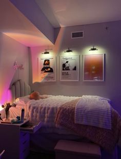 a bedroom with purple lighting and pictures on the wall above the bed in front of it