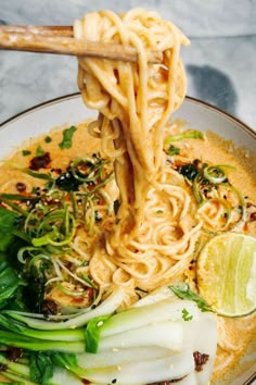 a bowl filled with noodles and vegetables on top of a table