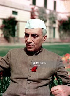 an old man wearing a white turban and sitting in a green chair outside