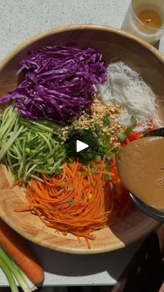 a wooden bowl filled with different types of vegetables and dipping sauce on top of it