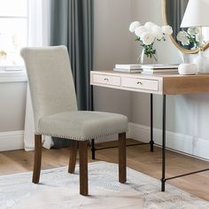 a desk with a mirror, lamp and chair in front of a window on the floor