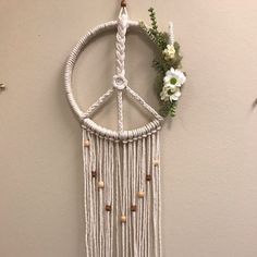 a peace sign hanging from the side of a wall with beads and flowers on it