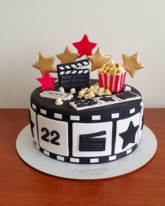 a black and white cake decorated with popcorn, stars and movie claps on top