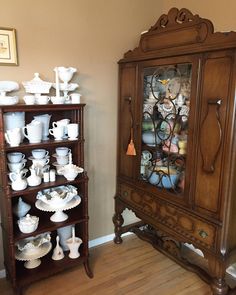 an antique china cabinet with glass doors in a living room area next to a wooden floor