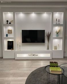 a modern living room with white walls and built - in shelving, coffee table and vases