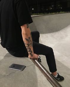 a man sitting on top of a skateboard ramp next to a metal pole with writing on it