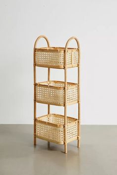 a bamboo shelf with wicker baskets on the top and bottom, against a white wall