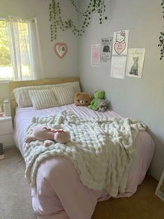 a bed with two teddy bears on it in a bedroom next to a window and plants