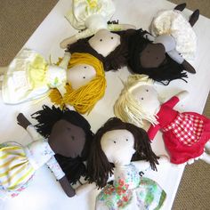 several dolls are laid out in a circle on the floor next to a white table cloth