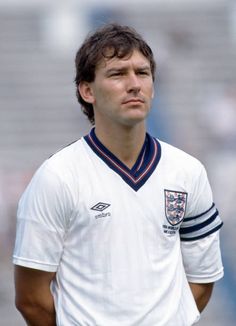 a man standing on top of a soccer field wearing a white shirt and blue shorts