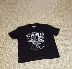 a black t - shirt with the words cash and eagle on it sitting on a bed