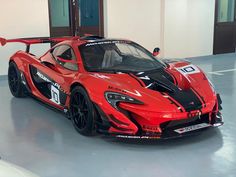 a red sports car is parked in a large room with white walls and flooring