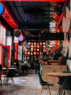 the interior of a restaurant with tables, chairs and neon lights hanging from the ceiling