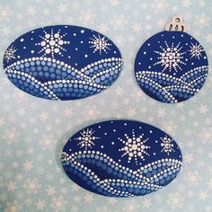 three blue ornaments with white snowflakes on them