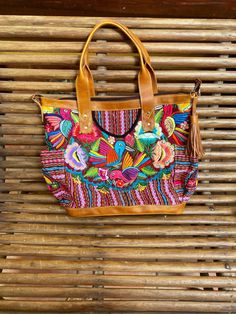 A stunning happy and unique piece that will add charm and beauty to any traveling . Leather and a beautiful handmade Huipil Weaved on a backstrap loom, it takes more than six months to complete one and is a unique piece that will add color and style to any wardrobe , A huipil is a women's blouse worn by Mayan women from Guatemala. Each handmade Huipil its unique since it depends on the inspiration of the weaver. Size inches wide 19 X tall 14 inches wide 6 inches depth 5 metal feet at the bottom Multicolor Hand Tooled Travel Bags, Bohemian Leather Shoulder Bag For Vacation, Leather Bohemian Shoulder Bag For Vacation, Embroidered Natural Shoulder Bag For Travel, Handmade Multicolor Embroidery Shoulder Bag For Travel, Embroidered Brown Shoulder Bag For Vacation, Brown Embroidered Shoulder Bag For Vacation, Huipil Pattern, Mayan Women