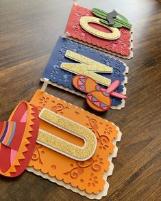 three paper cutouts on top of a wooden table