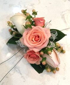 a pink rose and white calla lilies on a marble countertop with greenery